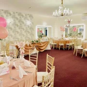 Bright banquet hall with round tables and pink balloon decorations
