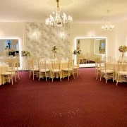 Spacious event salon with chandeliers and neatly arranged guest tables